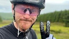 El piloto de Mountain Bike Rab Wardell haciendo el gesto de la victoria con los dedos, vestido para ir en bici, en los Glentress MTB Trails, el 27 de junio del 2022. 