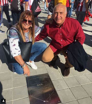 Los padres de Saúl José Antonio Ñíguez "Boria" y Pilar Esclapez posan con la placa de su hijo en el Wanda Metropolitano. 