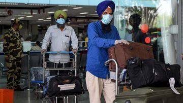 Indian nationals after returning from Sharjah in the United Arab Emirates (UAE) with a special flight arrive before boarding a bus taking them to a quarantine facility, amid concerns over the spread of the COVID-19 coronavirus, at Sri Guru Ram Dass Jee In