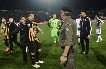 A policeman (R) orders AEK defender Vassilis Lampropoulos (L) and other players to leave the pitch, during incidents following the referee's decision to disallow PAOK a last minute goal on March 11, 2018 during the Greek Superleague football match PAOK Th