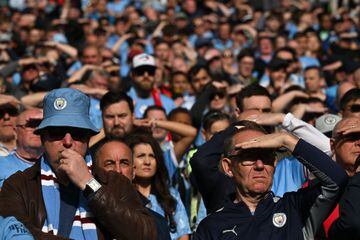 Manchester City fans shield their eyes from the sun 