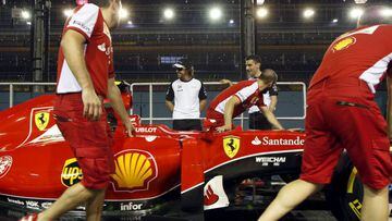 Alonso speaks to his former teammates from Ferrari as they push a car past at the pit ahead of the Singapore F1 Grand Prix night race in Singapore September 17, 2015. 