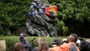 Reporters stand under the statue of a lion, decorated with a face mask, as the National Zoo reopens for socially-distanced patrons for the first time since the start of the coronavirus disease (COVID-19) outbreak in Washington, U.S. July 24, 2020. REUTERS