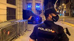 Un polic&iacute;a nacional patrullando por la calle de Barcelona, frente a la comisar&iacute;a de Via Laietena, con una furgoneta de antidisturbios al fondo. 