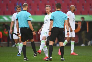 Wolfsburg's German midfielder Maximilian Arnold (C) taps feet with  assistant referee Dominik Schaal (L) after  the German first division Bundesliga football match FC Augsburg v VfL Wolfsburg on May 16, 2020 in Augsburg, southern Germany, as the season re