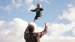 Padre lanzando a su bebé por los aires en el teaser del festival BANFF, con el cielo medio nublado.