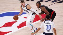 Kissimmee (United States), 20/08/2020.- Dallas Mavericks guard Luka Doncic (L) dribbles by LA Clippers forward Kawhi Leonard (R, top) as Dallas Mavericks guard Seth Curry (R, bottom) looks on during the second half of the NBA basketball first-round playof