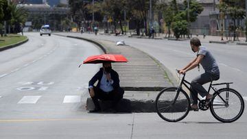 A merchant rests under an umbrella during as merchants block a road to protest against the Colombian government&#039;s mandatory quarantine imposed for next weekend in some main cities of the country to prevent Covid-19 contagions, in Bogota, on April 16, 2021. (Photo by Raul ARBOLEDA / AFP)