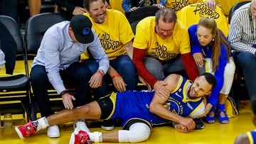 Golden State Warriors guard Stephen Curry is assisted by court side fans