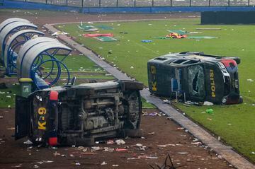 Coches de policía volteados permanecen sobre el terreno de juego del estadio Kanjuruhan en Malang, Indonesia.
