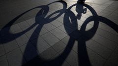 A visitor and the Olympic Rings monument cast shadows on the ground outside the Japan Olympic Committee (JOC) headquarters near the National Stadium, the main stadium for the 2020 Tokyo Olympic Games that have been postponed to 2021 due to the coronavirus