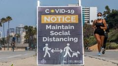 A woman wearing a facemask jogs near a notice about maintaining social distance in Long Beach, California, on July 14, 2020. - California&#039;s Governor Gavin Newsom announced a significant rollback of the state&#039;s reopening plan on July 13, 2020 as 