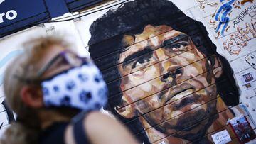 A woman stands in front of a mural of Diego Maradona outside Argentinos Juniors Club at Paternal neighbourhood on November 27, 2020 in Buenos Aires, Argentina.