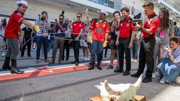 Ferrari's Monegasque driver Charles Leclerc (L), with Ferrari's Spanish driver Carlos Sainz Jr. (55), tries to lasso at cow skull in the paddock ahead of the United States Formula One Grand Prix at the Circuit of the Americas in Austin, Texas