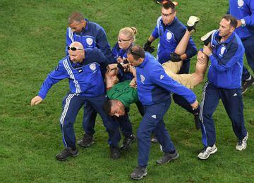 Pitch invader at Poland - Portugal match is hauled away.