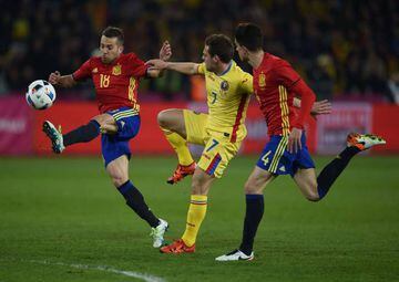 Jordi Alba and Marc Bartra of Spain vie for the ball against Adrian Popa of Romania.