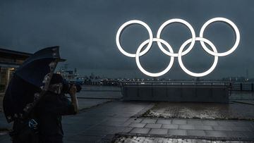 YOKOHAMA, JAPAN - JUNE 30: A man takes a photograph of the Olympic Rings at Akarenga Park on June 30, 2021 in Yokohama, Japan. With less than one month to go before the start of the Tokyo Olympic Games, final preparations are being made to venues despite 
