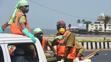Municipal workers wearing facemasks travel at the back of a vehicle during a government-imposed nationwide lockdown as a preventive measure against the COVID-19 coronavirus, in Mumbai on April 9, 2020. (Photo by Punit PARANJPE / AFP)