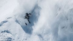 Un esquiador levantando nieve en una monta&ntilde;a. 