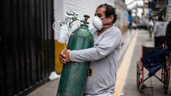 A man carries an oxygen cylinder to deliver it to a relative at the area of respiratory diseases of the 2 de Mayo Hospital in Lima on June 3, 2020, amid the COVID-19 coronavirus pandemic. - Relatives of people with COVID-19 are desperate for oxygen to keep their loves ones alive in Peru, where patients have been dying for lack of oxygen. (Photo by Ernesto BENAVIDES / AFP)