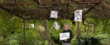 Javier Mariscal posa con varios dibujos de las mascotas Cobi y Petra en el jardín de su estudio. 