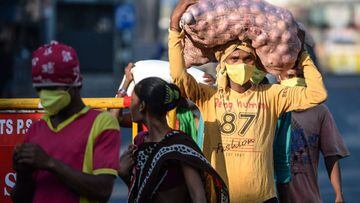 Migrant workers carrying sacks of groceries distributed at their workplace walk on a street during a government-imposed nationwide lockdown as a preventive measure against the COVID-19 coronavirus, in Chennai on April 4, 2020. (Photo by Arun SANKAR / AFP)