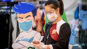 An employee wearing a facemask and a shield looks at her phone at the Central World shopping mall as it reopened after restrictions to halt the spread of the COVID-19 coronavirus were lifted in Bangkok on May 17, 2020. (Photo by Mladen ANTONOV / AFP)