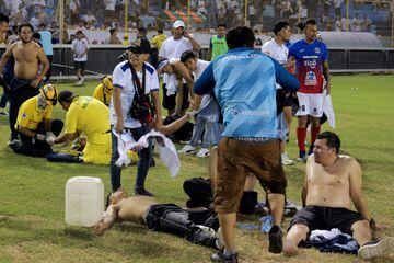 Aficionados heridos reciben ayuda de otros hinchas tras la avalancha en el estadio.