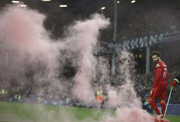 Soccer Football - Premier League - Everton v Liverpool - Goodison Park, Liverpool, Britain - December 1, 2021 A smoke bomb is removed from the pitch by a member of staff as Liverpool's Mohamed Salah celebrates scoring their third goal