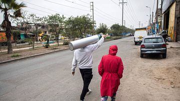 A relative of a COVID-19 patient carries an oxygen cylinder after it was recharged in Villa Maria del Triunfo, in the southern outskirts of Lima, on July 29, 2020. (Photo by ERNESTO BENAVIDES / AFP)