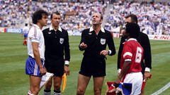 The two captains, France's Michel Platini (l) and Kuwait's Sa'ad Abdul Aziz Al-Houti (r), keep their eyes on the money as referee Miroslav Stupar (c) tosses the coin before the match  (Photo by Peter Robinson - PA Images via Getty Images)