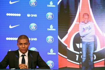Paris Saint-Germain's new forward Kylian Mbappe  is pictured next to a childhood photo of himself in front of a PSG logo as he speaks during a press conference on his presentation at the Parc des Princes stadium in Paris on September 6, 2017.