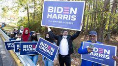 NORCROSS, GA - NOVEMBER 03: Gwinnett county voters including Menar Hague (C) wave Biden-Harris campaign signs at the entrance to Lucky Shoals Park polling station on November 3, 2020 in Norcross, Georgia. After a record-breaking early voting turnout, Amer