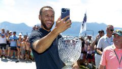 El jugador de los Golden State Warrios de la NBA Stephen Curry de graba un vídeo con el móvil con el trofeo de campeón del American Century Championship en el Edgewood Tahoe Golf Course.