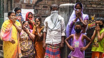 People protecting their faces stand looking as a man dressed up as Hindu deity of death Yamaraj to raise awareness about the coronavirus walks past during a government-imposed nationwide lockdown as a preventive measure against the COVID-19 coronavirus, i