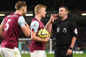 Referee Michael Oliver (R) waits for a VAR decision match between Burnley and Chelsea at Turf Moor.