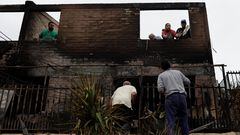 Miembros de la familia limpian la casa quemada de su madre y su abuela tras la propagación de los incendios forestales.