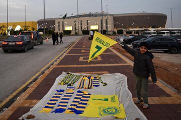 Un niño sostiene una bandera con el nombre de Ronaldo mientras vende souvenirs frente al estadio Mrsool Park donde se está presentando al futbolista portugués Cristiano Ronaldo, en Riad, Arabia Saudí,