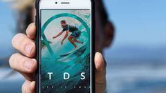 Un surfista muestra el tel&eacute;fono m&oacute;vil con la app de Todosurf, de previsi&oacute;n de oleaje. 