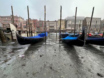 Las góndolas están ancladas a lo largo de un canal durante una marea baja en la ciudad laguna de Venecia, Italia.