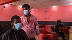 Kofi (C), a barber, resumes work after the partial lockdown in parts of Ghana to halt the spread of the COVID-19 coronavirus was lifted in Accra, Ghana on April 20, 2020. - The streets of Accra buzzed with life following President Nana Akufo-Addo&#039;s a