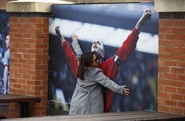 In Manchester | Woman cuddles photo of David Beckham in front of Old Trafford Stadium.