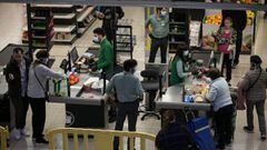 Cajeros de un supermercado atienden a sus clientes con mascarillas y guantes.