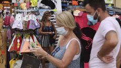 People wearing masks stop at a souvenir shop along Fesch Street in Ajaccio&#039;s touristic district on August 4, 2021, as health officials activated an emergency plan on the Mediterranean island of Corsica as a fourth wave of Covid infections spread acro