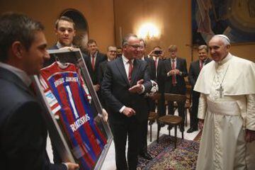 El Papa Francisco mientras recibe una camiseta firmada firmada por todos los jugadores del Bayern Munich de manos de Manuel Neuer y Philipp Lahm.