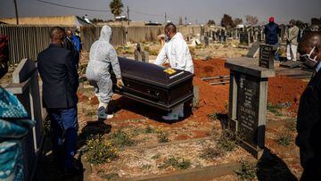 Relatives observe undertakers moving a casket containing the remains of a COVID-19 coronavirus patient during a funeral at the Avalon cemetery in Soweto, on July 24, 2020. (Photo by Michele Spatari / AFP)