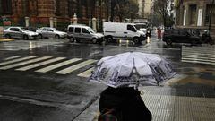 A woman walks under the rain with an umbrella with images of the Eiffel Tower and the Statue of Liberty, in Buenos Aires on June 30, 2020, a day before authorities tighten virus lockdown measures against the spread of the novel coronavirus, COVID-19. - The country went into lockdown on March 20 to help prevent the spread of the novel coronavirus, but those measures have been gradually eased in recent weeks. However, following a spike in coronavirus cases in the capital, a new lockdown has been imposed on the greater Buenos Aires area -- home to more than a third of the country&#039;s 44 million people -- from July 1-17. (Photo by Juan MABROMATA / AFP)