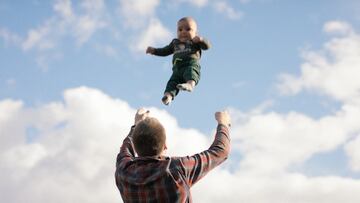 Padre lanzando a su bebé por los aires en el teaser del festival BANFF, con el cielo medio nublado.