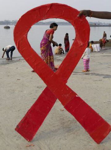 Un activista sostiene un lazo rojo que hace referencia al virus del sida durante el Día Mundial de esta enfermedad en Calcuta, la India.