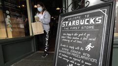 Un cliente sale de la primera tienda Starbucks, el martes 7 de julio de 2020, en Pike Place Market en Seattle.